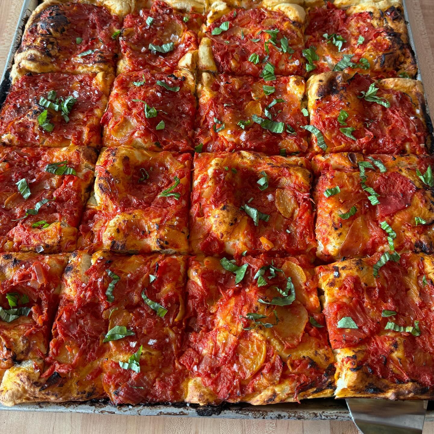 Vegan tomato focaccia with basil sprinkled on top.